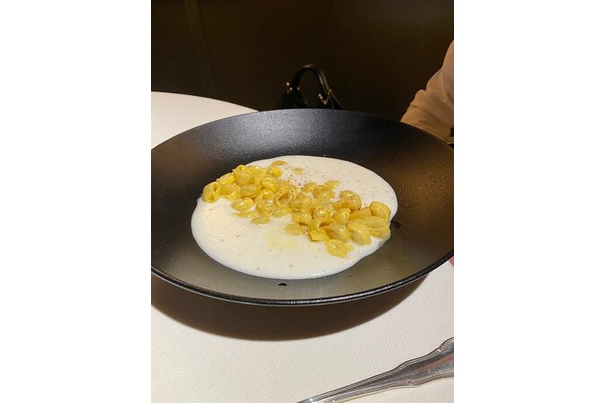 Donna anziana mescola pasta e fagioli in una pentola grande.