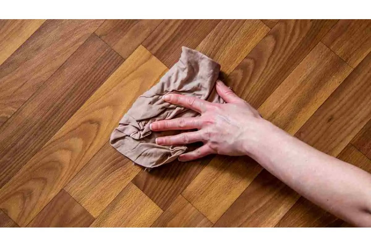 Donna pulisce il parquet con un panno morbido in soggiorno luminoso.