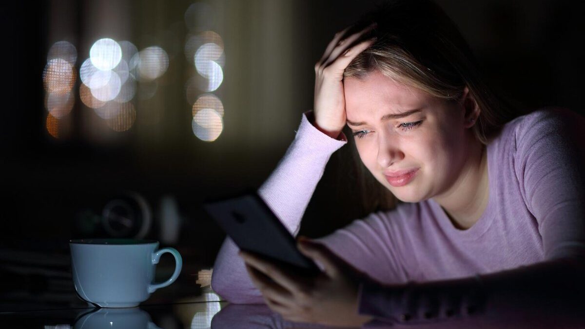 Persona che scorre sul telefono con espressione triste.